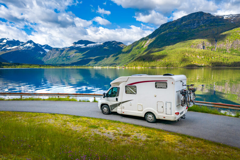 Wohnmobil mit Fahrrädern an einem klaren Bergsee in Norwegen